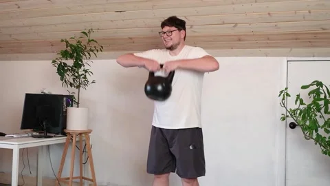 Man training with kettlebell at home while working from the computer from home Stock Footage 310755830