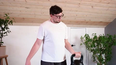 Man training with kettlebell at home while working from the computer from home Stock Footage 310755974