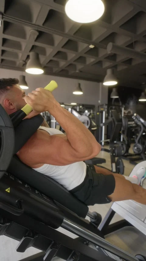 Man training legs on hack squat machine in gym Stock Footage 328122904