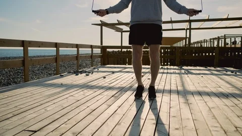 Man is training outdoors, using jumping rope, close-up of legs Stock Footage 112019388