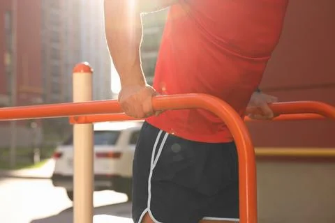 Man training on parallel bars at outdoor gym on sunny day, closeup Foto stock