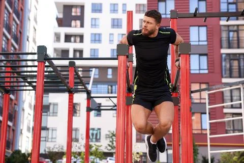 Man training on parallel bars at outdoor gym Stock Photos