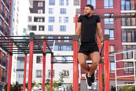 Man training on parallel bars at outdoor gym Stock Photos
