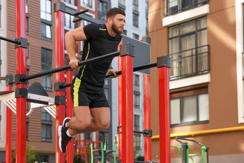 Man training on parallel bars at outdoor gym, low angle view Stock Photos