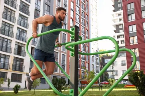 Man training on parallel bars at outdoor gym, low angle view Stock Photos