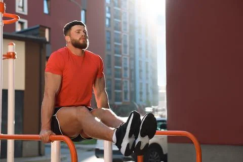 Man training on parallel bars at outdoor gym on sunny day Stock Photos