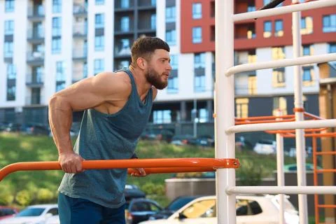 Man training on parallel bars at outdoor gym Stock Photos