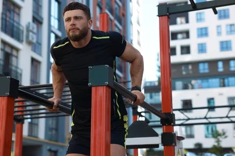 Man training on parallel bars at outdoor gym, low angle view Stock-Fotos