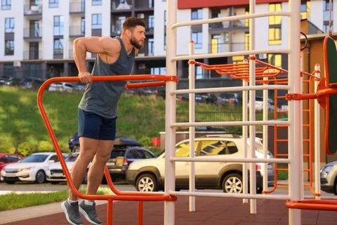 Man training on parallel bars at outdoor gym Stock Photos