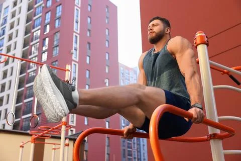 Man training on parallel bars at outdoor gym, low angle view Stock-Fotos