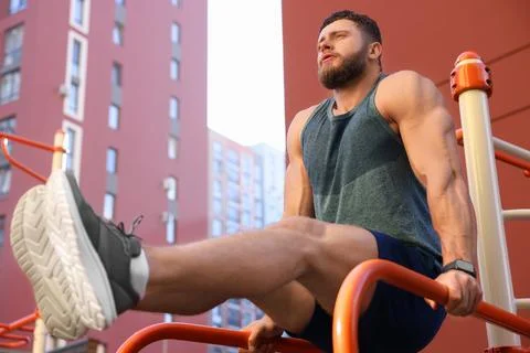 Man training on parallel bars at outdoor gym, low angle view 写真素材