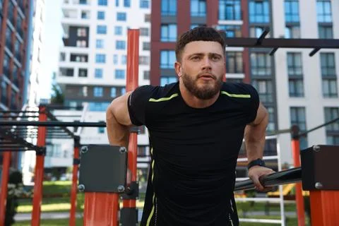Man training on parallel bars at outdoor gym Stock Photos