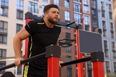 Man training on parallel bars at outdoor gym, low angle view Stock Photos