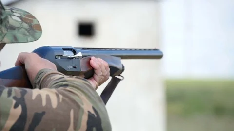 Man trains skeet shooting, while aiming somewhere from his shotgun outdoors Stock Footage 76054107