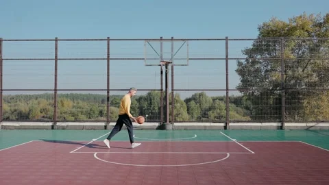 Man trains throwing basketball ball in basket on a street court on a sunny day Vídeo Stock 166835680
