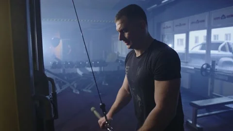 A man trains triceps on the exercise machine on the background of the hall. Stock Footage 234422540