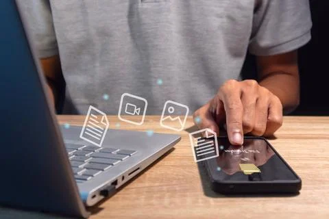 A man transfer files between mobile phone and laptop. Backup, Copy file and.. Stock Photos