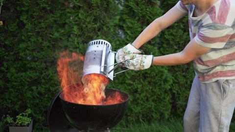 A man is transfering hot burning coal lumps into a garden grill from a chimney Stock Footage 246661409