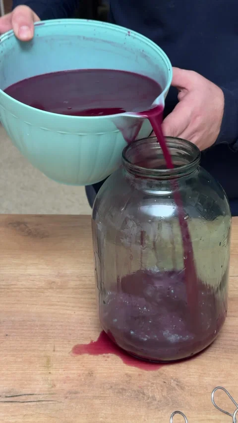 A man transfers fermented grape juice into a jar for further fermentation, .. Stock Footage 321122761