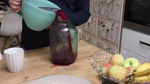 A man transfers fermented grape juice into a jar for further fermentation, .. Stock Footage 321122813