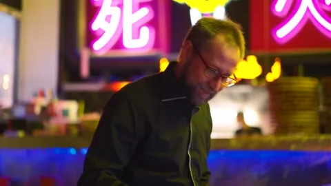 Man transfixed by pinball machine, neon lights reflect addiction. He's lost in Stock Footage 271297848
