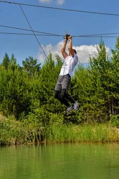 Man is transported on rope through the river Stock Photos