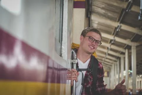 Man traveler with backpack shows thumb up on train at railway station. backpa Stock Photos