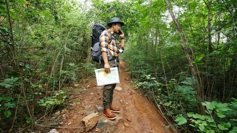 Man traveler with backpack talking on a mobile phone in the natural forest Video stock 128099359