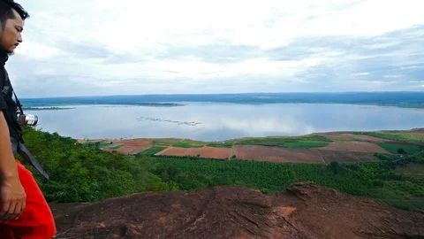 Man traveler with backpack using camera taking a photo on the edge of cliff Stock Footage 128215329