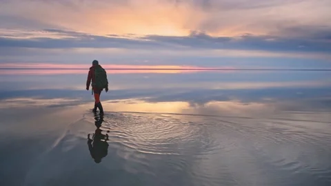 Man traveler with backpack walking on the salt lake at sunset. Stock Footage 191439734