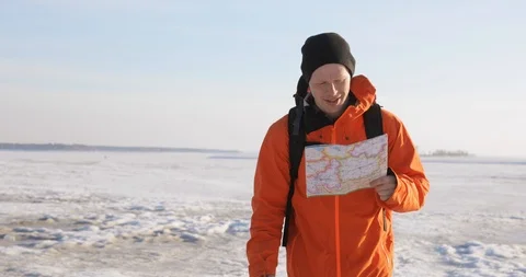 Man traveler with map in hands is pointing the route on a snow covered area in Stock Footage 106086494