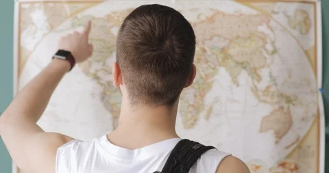 Man traveller is looking at map and pointing places to visit, back view. Travel Stock Footage 108018105