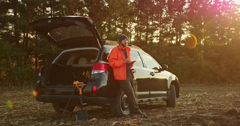 A man-treasure hunter is standing next to a car with a phone in his hands. Stock Footage 272318887