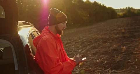 A man-treasure hunter is standing next to a car with a phone in his hands. Stock Footage 272318895