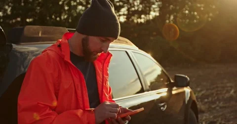 A man-treasure hunter is standing next to a car with a phone in his hands. Stock Footage 272318947