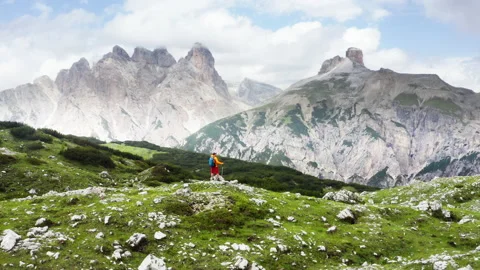 Man trekker standing with backpack and trekking poles by green mountain hill and Stock-Footage 220500837