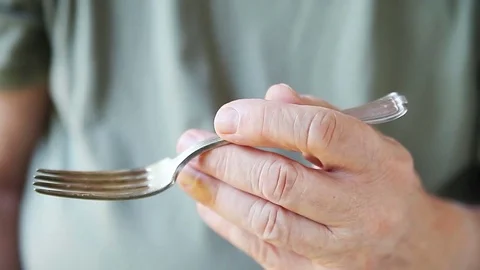 Man with tremor holds fork Stock Footage 79234876