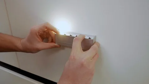 A man tries different lights on the wall Stock-Footage 128104406