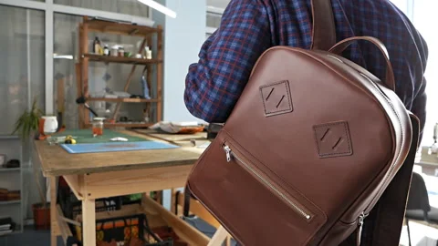A man tries on a handmade leather backpack. Choosing a comfortable backpack for Stock Footage 126655353