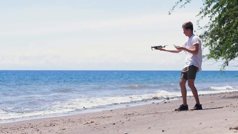 A man tries to launch a drone at the beach but the drone fell down. Stock Footage 118571753