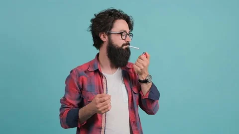 Man tries to light a cigarette and returns with a surprised look to the camera. Stock Footage 146033963