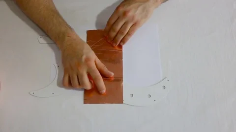A man tries on a piece of copper foil on guitar pikgard. Top view of male hands, Stock Footage 84595833
