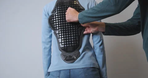 Man tries on a plastic back protector for a motorcycle jacket on a woman 動画素材 205262444