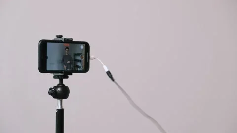 Man tries to record a vlog but struggles with the inconvenience of a wired Stock Footage 311809988