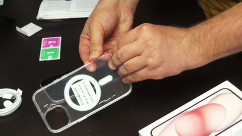 The man tries on a silicone cover on an iPhone 15. Makes the unpacking of t.. Stock Footage 277546243