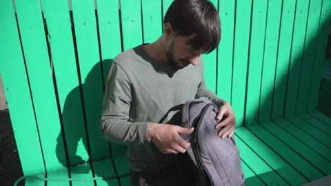 Man tries to zip outdoor backpack with splitting zipper. Stock Footage 330534890