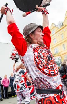 Man in trilby fedora hat playing on a drum raised above his head. Stock Photos