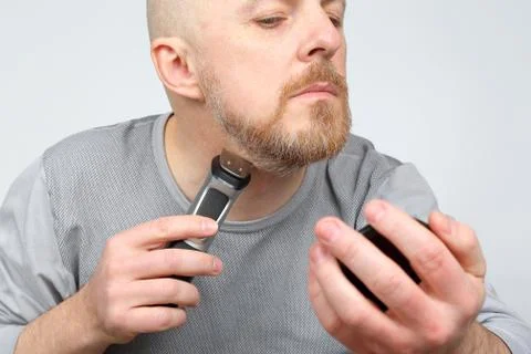 Man trimmer corrects his beard. Stock Photos