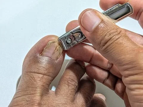 Man trimming toenail using clipper for foot care and hygiene maintenance at home Stock Photos
