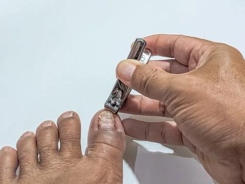 Man trimming toenail using clipper for foot care and hygiene maintenance at home Stock Photos